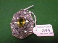 A large oval white metal Brooch set with diamante and a single central oval yellow stone