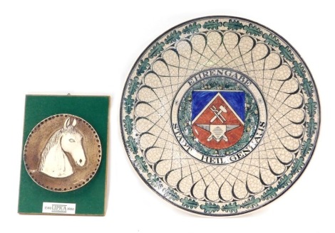 A German studio pottery charger, maker's initials R/SK, decorated to the front and inscribed Ehrengabe Stadt Heiligenhaus, 37cm diameter, and a Yugoslavian commemorative plaque decorated with a horses head in profile. (2)