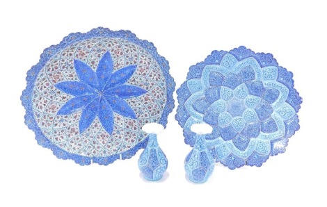 Middle Eastern enamel wares, comprising a charger and matching vases, on a dark and light blue ground, stamped Made in Iran on copper, 30cm diameter, and a further charger, heavily decorated, 34cm diameter. (4)