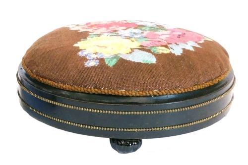 A Victorian ebonised and gilt metal circular footstool, with a later woolwork padded top, on ceramic bun feet, 28cm diameter.