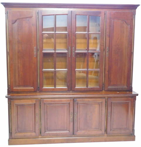 A Continental walnut bookcase, the top with a moulded cornice above two glazed doors, flanked by two doors, with brass hinges, the base with four panelled doors, on a plinth, 114cm high, 205cm wide, 50cm deep.