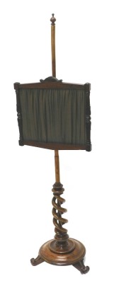 An early Victorian walnut pole screen, the associated rosewood banner inset with pleated fabric, on a part spirally turned column, circular moulded base and scroll feet, 145cm high.