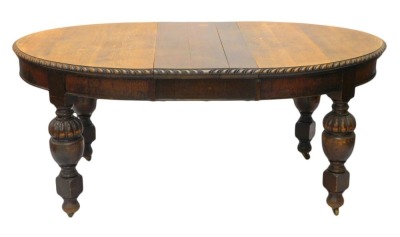 An early 20thC oak extending dining table, the oval top with a gadrooned border on bulbous cup and cover turned supports, 176cm high, 103cm wide. (AF)