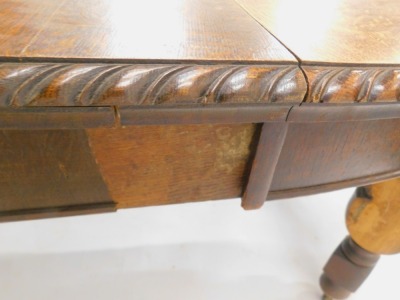 An early 20thC oak extending dining table, the oval top with a gadrooned border on bulbous cup and cover turned supports, 176cm high, 103cm wide. (AF) - 3