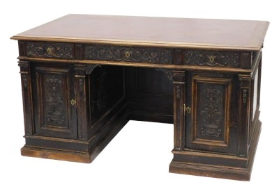 A Continental carved kneehole oak desk, the rectangular top with an ox blood red leatherette inset, with a moulded edge above arrangement of three frieze drawers and two panelled doors, on plinth, 83cm high, 153cm wide, 92cm deep. (AF)