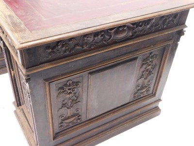 A Continental carved kneehole oak desk, the rectangular top with an ox blood red leatherette inset, with a moulded edge above arrangement of three frieze drawers and two panelled doors, on plinth, 83cm high, 153cm wide, 92cm deep. (AF) - 4