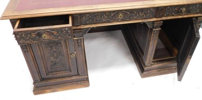 A Continental carved kneehole oak desk, the rectangular top with an ox blood red leatherette inset, with a moulded edge above arrangement of three frieze drawers and two panelled doors, on plinth, 83cm high, 153cm wide, 92cm deep. (AF) - 5