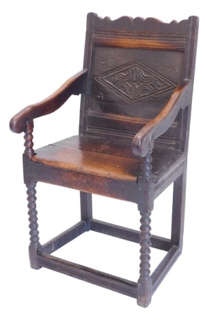 An oak Wainscote chair, the panelled back carved with lozenge, with shaped arms, solid seat, on bobbin turned supports with plain stretchers, in part 17thC.