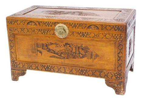 An Eastern carved camphor chest, decorated with landscapes, leaves, etc., on bracket feet, 101cm wide.