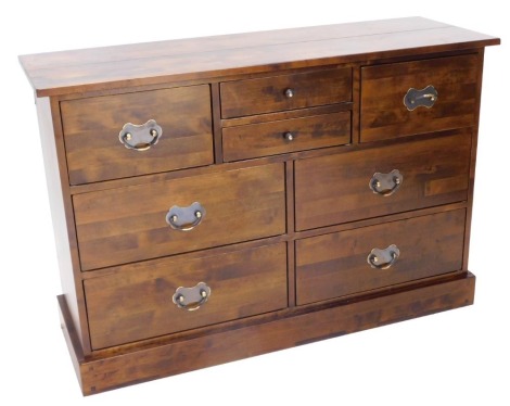 A stained pine chest of drawers, with a narrow planked top above an arrangement of two short, two deep and four large drawers, each with drop handles, on a plinth, 85cm high, 128cm wide, 43cm deep.