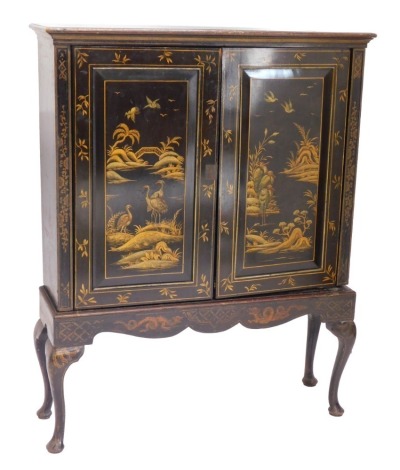 A black Japanned side cabinet, decorated overall with storks in river landscapes in gilt, the top with a moulded cornice above two panelled doors enclosing shelves, on cabriole legs with pad feet, 142cm high, 112cm wide.