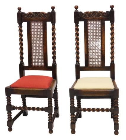 A pair of 1920s oak side chairs, each with a carved crest, above a chained panel flanked by spirally turned supports, with a padded seat, on turned supports.