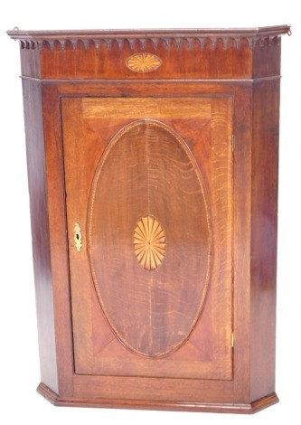 An early 19thC oak mahogany and marquetry hanging corner cabinet, with a moulded cornice above a panelled door, 118cm high, 83cm wide.