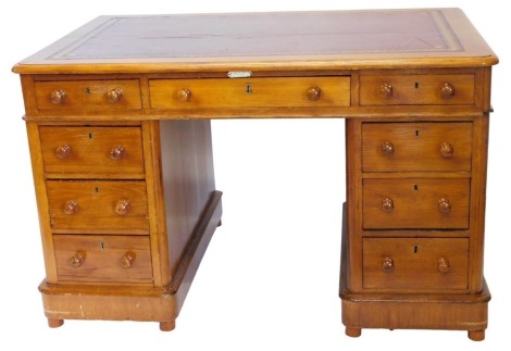 A late 19th/early 20thC oak pedestal desk, the rectangular top with a maroon leather insert above an arrangement of nine drawers, each with two turned handles, on a plinth, with small bun feet, 76cm high, 120cm wide.