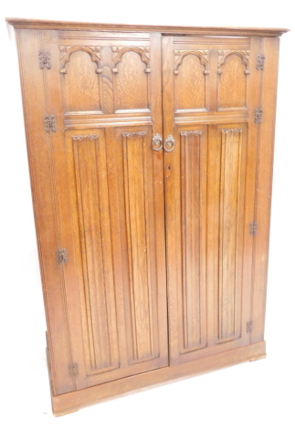 An oak wardrobe, the top with a blind effect frieze above elaborately carved panel door, flanked by fluted pilasters on bun feet, 196cm high, 89cm wide.