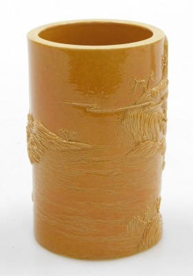 An ochre glazed porcelain brush pot, of cylindrical form, carved in relief with seated buddha in a river landscape, four character Qianlong seal mark, 12.5cm high. - 3