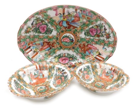 A 20thC Chinese Canton famille rose porcelain meat platter, of twin handled oval form, decorated with reserves of figures in an interior, birds and flowers, on a ground decorated with butterflies and flowers, 35cm wide, together with a pair of similarly d