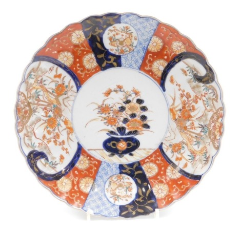 A Japanese Meiji period Imari dish, of fluted form, centrally decorated with an urn of flowers, within a border with reserves of flowers and rabbits, 30cm wide.