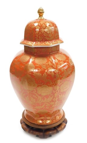 A 20thC Japanese Shibata Toki porcelain vase and cover, of octagonal form, gilt decorated with flowers, on a red ground, with wooden stand, 40.5cm high.