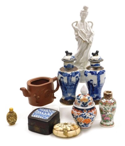 A group of Oriental ceramics and collectables, including a blanc-de-chine figure of Guanyin, an Imari jar and cover, a pair of blue and white vases and covers, decorated with figures, a Yixing teapot, and a bone box. (8)