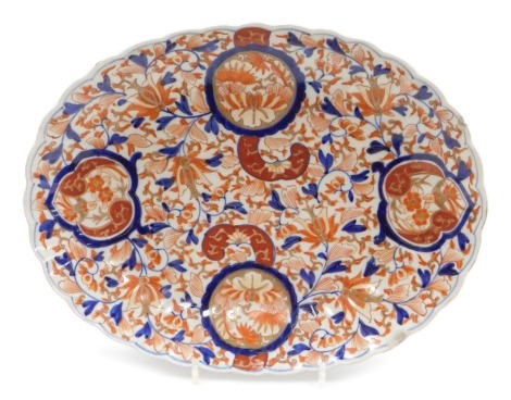 A Meiji period porcelain Imari dish, of oval fluted form, decorated all over with flowers and leaves, 36cm wide.