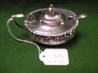 A silver mustard pot with rococo style decoration