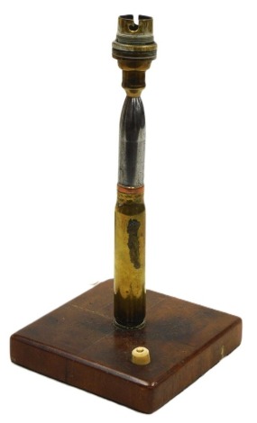 A WWI trench craft brass 20mm cannon shell table lamp, mounted on a square wooden base, with press button switch.