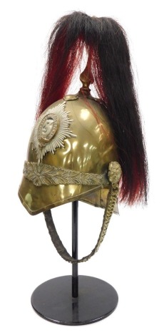 A British 1871 pattern Third Dragoon Guards trooper's helmet, in brass with laurel leaf decoration, with chin strap and fluted plume holder with black and red horse hair plume, and the stand.