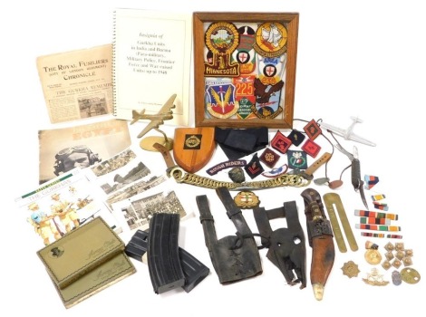 An assortment of various military interest, including a model aluminium Spitfire, a brass trench craft model of a Hampden Bomber, various cloth badges, two Army Club Sandhurst cigarette boxes, medal ribbons, rank insignia, ID tags, Jack knife, helmet chin