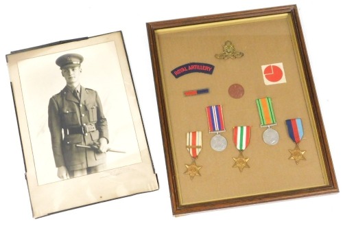 Royal Artillery interest, comprising photograph of a Royal Artillery officer, and a medal group comprising 1939-45 War medal, Defence medal, Africa Star, Italy Star and 1939-45 Star, with ID tag, brass cap badge, etc., mounted and framed.