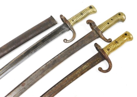 A French M1866 Chassepot bayonet, with brass grip and Yataghan blade, blade 57cm long, with steel scabbard and another French Chassepot bayonet, and another similar. (AF)(3)