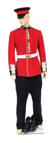 A Welsh Guards dress uniform, comprising red dress tunic, with white leather belt and bayonet scabbard, trousers, cap and boots, the tunic and trouser sizes height 72, chest 44 and waist 38, with mannequin display