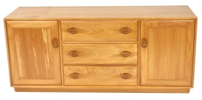 An Ercol light elm sideboard, with three central drawers, flanked by two cupboard doors, raised on a plinth base, 68cm high, 155cm wide, 43.5cm deep.