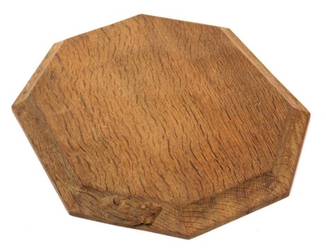 A Robert Thompson of Kilburn 'Mouseman' bread board, of octagonal form, carved to the side with a mouse, 30cm wide, 25cm deep.