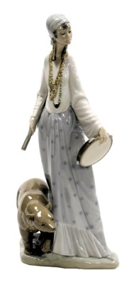 A Lladro porcelain figure of a lady, modelled standing with a stick and tambourine, alongside a bear, printed and impressed marks, 37cm high.