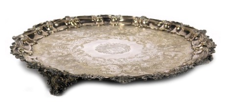 A Victorian silver plated pie crust salver, with floral and foliate engraving, central reserve armorial engraved, within a border of embossed scrolling leaves, raised on three scroll feet, 39cm wide.