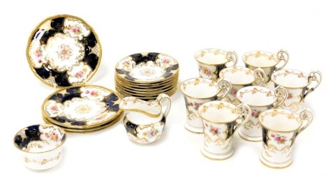 An early 20thC Coalport porcelain part coffee service, decorated with reserve floral sprays, on a cobalt blue ground, gilt heightened, printed marks, comprising cream jug, sugar bowl, eight coffee cups with scroll handles, saucers, and four biscuit plates