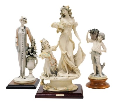 Three Giuseppe Armani Capodimonte figures, comprising an Art Deco lady aside an urn of bullrushes, raised on a square base, 34cm high, a boy carrying a basket of grapes, 27cm high, and a figure group of a lady and child carrying flowers, raised on a natur