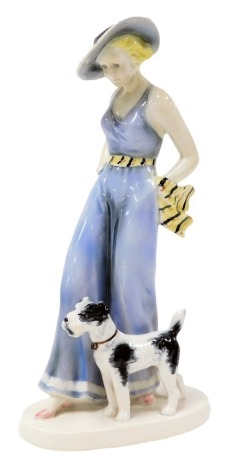 An Art Deco Continental pottery figure group, of a lady standing in summer attire, with a terrier, raised on an oval base, number 183, printed and impressed marks, 30cm high.