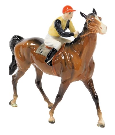 A Beswick pottery figure of a racehorse and jockey, number 24, the rider in yellow, black and red colours, printed mark, 25cm wide.