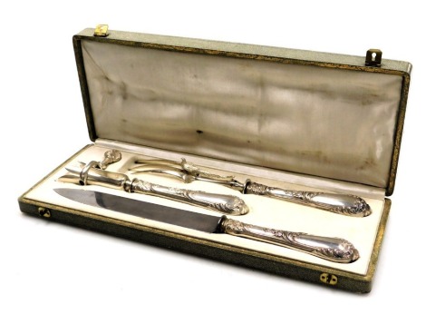 An early 20thC French silver handled carving set, with embossed floral and foliate decoration, comprising a fork, knife, and hand brace, cased, bears marks.