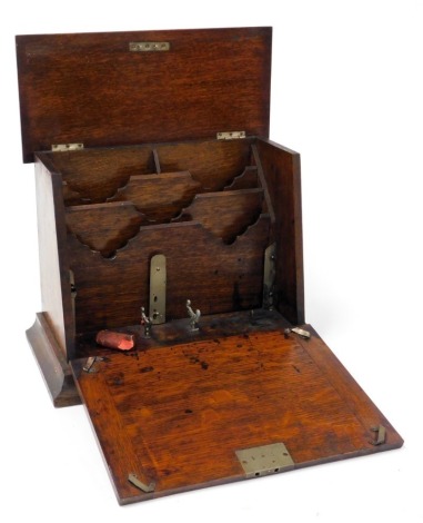 A Victorian oak stationary rack, the lid with a monogrammed brass shield escutcheon, and drop front, both opening to reveal a fitted interior, raised on a plinth base, with brass presentation plaque, 26cm high, 34cm wide, 18.5cm deep.