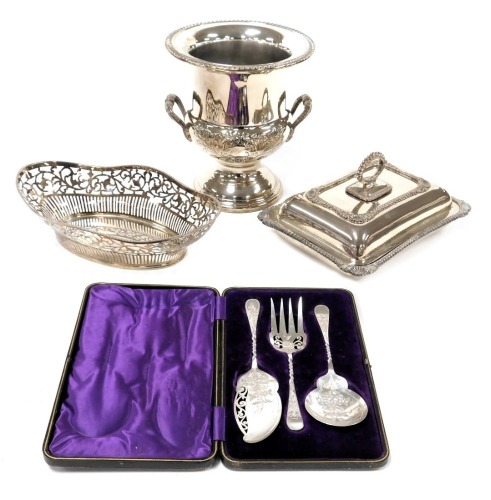 A silver plated wine cooler, and ice tongs, plated entrée dish and cover, oval pierced basket, and dessert servers, cased. (4)