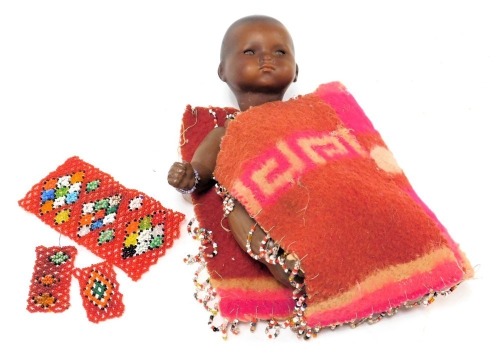 An Armand Marseilles bisque head black doll, model 341 12/0K, with a Zulu fabric and beadwork applied tunic, 21.5cm high.