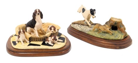 A Border Fine Arts sculpture of a Springer spaniel and puppies, in a basket, designed by Ayres, on a wooden stand, and further sculpture, of a terrier chasing a rabbit, designed by A Wall, on a wooden stand. (2)