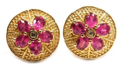 A pair of ruby and white stone set earrings, of five petalled flower head form, on a silver gilt circular mount, stamped 925.