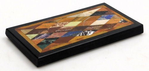 A 19thC Grand Tour Pietra Dura specimen paperweight, inset with agates, lapis lazuli, blue john and other stones, within a slate surround, 22cm wide, 11.5cm deep.