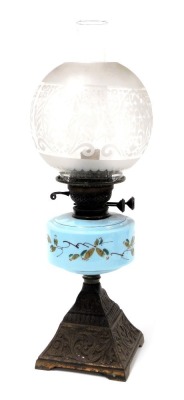 An early 20thC cast iron oil lamp, with a turquoise glass reservoir, painted with flowers, glass chimney and etched glass shade, 54.5cm high.