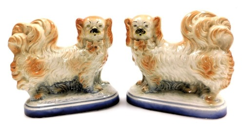 A pair of late 19thC pottery figures of Pekingese, naturalistically modelled on an oval base, 21cm wide.