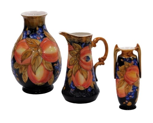 An Old Tupton Ware pottery vase, of baluster form, tube line decorated with fruit, printed mark, 29cm high, together with a twin handled vase, 20cm high, and a water jug, 24cm high. (3)